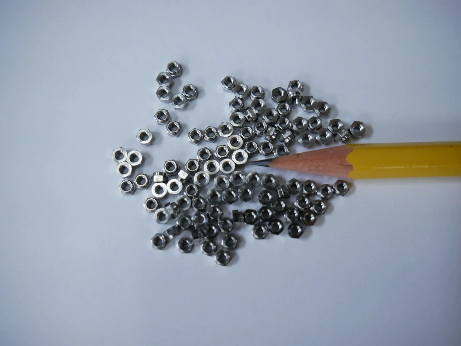 Batch of machined nuts with pencil for scale – Chesapeake CNC