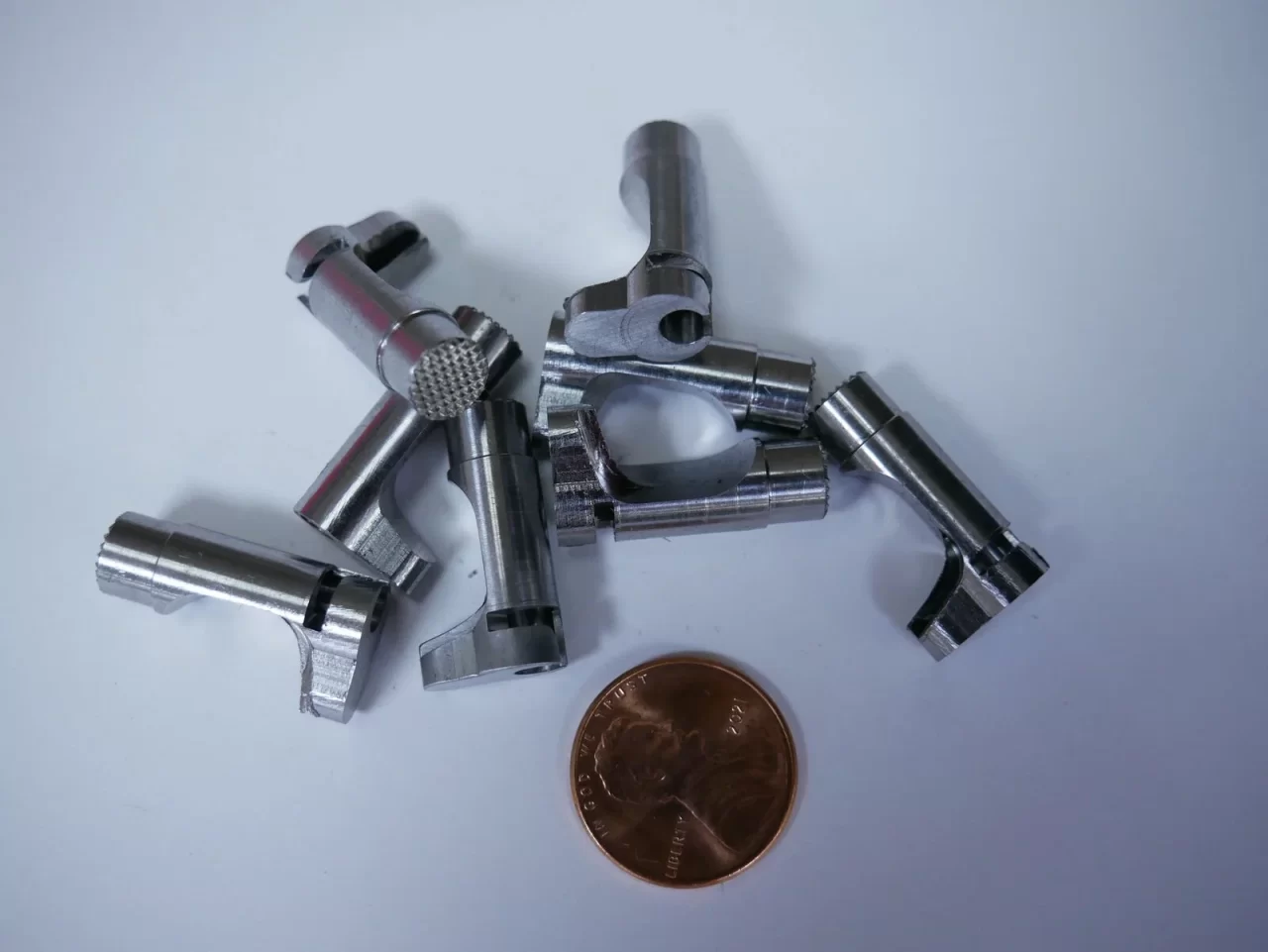 Precision-turned CNC components with penny for scale – Chesapeake CNC