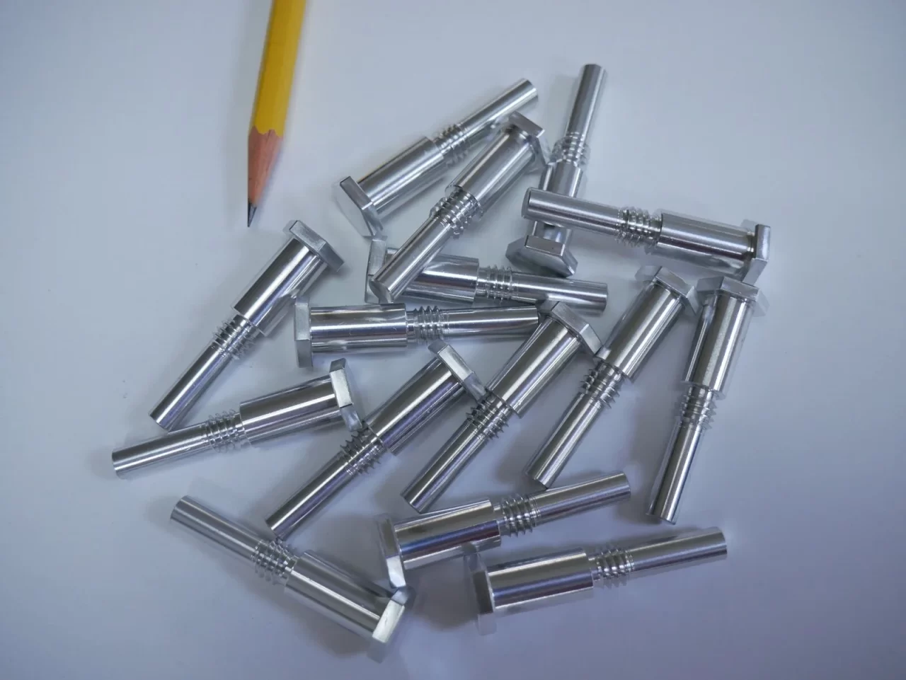 Swiss screw machined shafts with pencil for scale – Chesapeake CNC