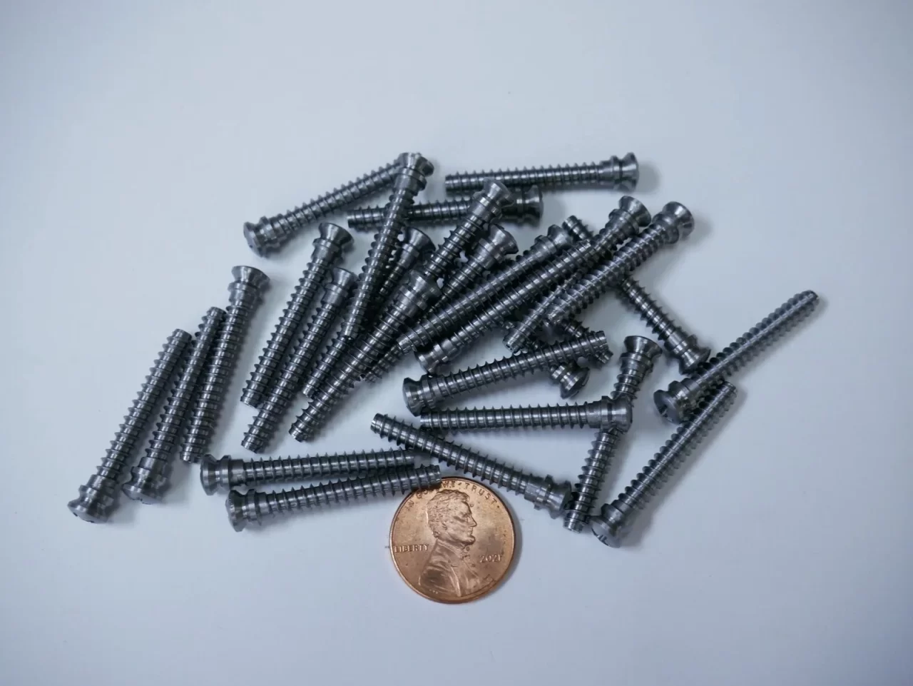 Threaded Swiss screw components with penny for scale – Chesapeake CNC